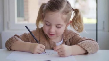 Küçük kız kağıda resim çiziyor.