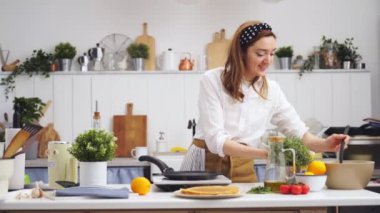 Profesyonel kadın aşçı, mutfakta kepçeyle tavaya krep hamuru koyuyor.