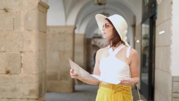 暑假期间 穿着帽子和太阳镜 头脑清醒的女性游客一边在街上散步一边阅读纸质地图 一边在城市里定位 — 图库视频影像