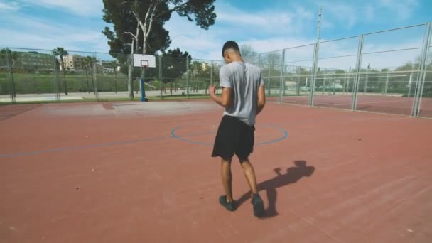 アフリカ系アメリカ人スポーツマンのボール投げを追跡し その後 スポーツグラウンドでバスケットボールのトレーニング中にリングに失敗したスラムダンクシュートを実行しようとします — ストック動画