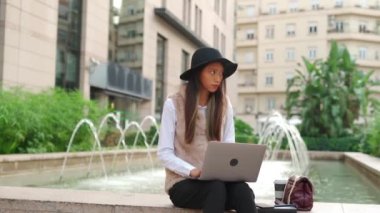 Konsantre olmuş İspanyol kadın internet sayfasında yazıyor. Binanın yakınında. Sokakta kahve servisi var.