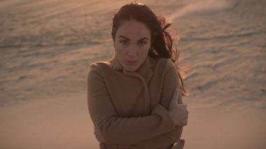 Levante 'de rüzgarlı bir günde kumsalda dikilen düşünceli, düşünceli, dondurucu bir kadın.