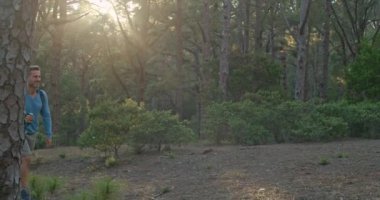 Sırt çantalı ve bastonlu yetişkin bir adamın gündüz vakti yeşil ağaçlıklarda yürüyüş yaparken fotoğrafını çekiyorum.