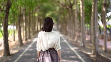 Tanya Shen Green Bisiklet Yolu 'nda yürüyen, yaz kıyafetli, kimliği belirsiz bir kadının arka görüntüsü.