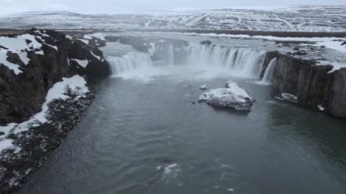 İzlanda 'da kasvetli bir günde kayalık kayalıklardan akan güçlü şelalenin nefes kesici manzarası.
