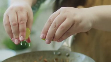 Anonim bir kadının mutfakta tavaya ekşi limon suyu ve erişte ektiği gerçek bir zaman.