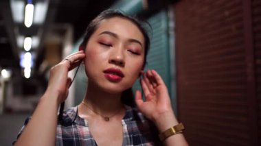 Kulaklıklı kadın yeraltı koridorunda duruyor.