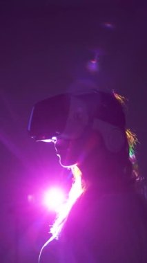 VR gözlüklü kadın siluetinin karanlık odada parlayan ışığa karşı yan görünüşü