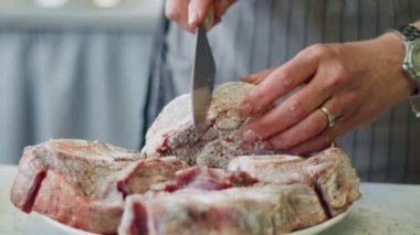 Gerçek zamanlı yüksek açılı, çiğ bıçaklı, ossobuco pişirirken çiğ dana inciği yiyen kimliği belirsiz bir kadın.