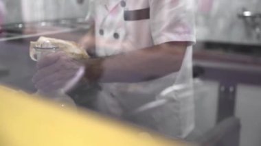 Restaurantın mutfağında leziz shawarma hazırlarken üniformalı, tanınmayan bir erkek aşçının etin üzerine sos dökmesi sayesinde.