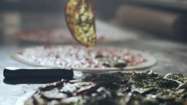 Kesilmiş erkek, pizzayı mermer tezgahta çeşitli sebzelerle hazırlıyor.