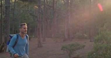 Sırt çantalı ve bastonlu yetişkin bir adamın gündüz vakti yeşil ağaçlıklarda yürüyüş yaparken fotoğrafını çekiyorum.