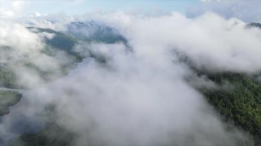 Yavaş çekim drone görüntüsü kıvrımlı nehir üzerinde yüzen yoğun kümülüs bulutları orman kıyıları ve kırsal evler