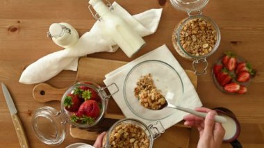 Mutfakta süt ve çilekle lezzetli sağlıklı kahvaltı hazırlarken cam kavanozdan klozete granola döken...