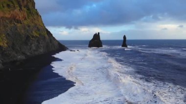 Fırtınalı İzlanda 'da fırtınalı bir günde dalgalı deniz dalgalarının dalgalı kayalıkların yanında yuvarlanışını ve sıçrayışını gösteren resimli drone görüntüsü.