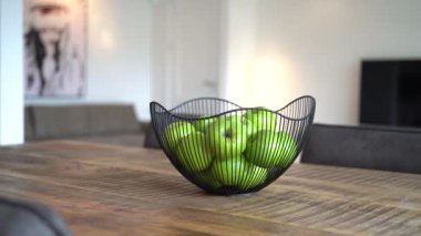 Modern oturma odasında yeşil elma dolu sepetle ahşap masayı kapat.