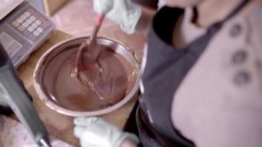 Yukarıdan gelen isimsiz bir işçiden kızılötesi termometre kullanarak klozetteki sıvı çikolatanın sıcaklığını ölçüyor.