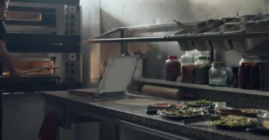 Tanınmayan erkek pizzacılar pizzacıda çalışırken taze pişmiş lezzetli pizzaları karton kutuya koyarlar.