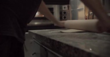 Adam mutfakta pizza pişiriyor.