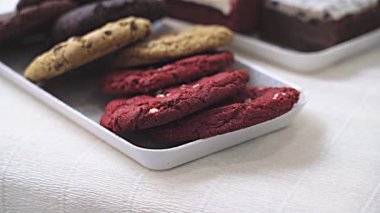 Yukardan gelen leziz kurabiyeler ve tatlı dilimler beyaz masada servis ediliyor.