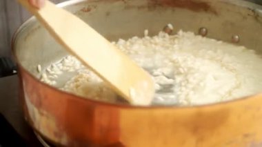 Mutfakta fırında yemek pişirirken tavada ahşap spatulayla acılı risotto karıştıran isimsiz bir şef.