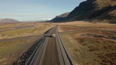 Güneşli bir günde, dağların yakınındaki vadide asfalt yolda giderken çekilmiş bir fotoğraf.
