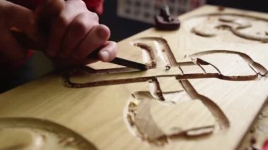 Tanımlanamayan erkek ahşap oymacı, atölyede çalışırken metal keski kullanarak ahşap süslemeler yapıyor.