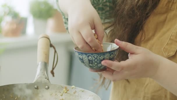 隐姓埋名的女菜鸟在厨房做饭的时候 慢吞吞地把切碎的坚果倒入热腾腾的锅中 — 图库视频影像