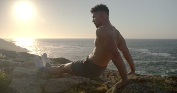 海岸での男子アスリート訓練や遠くを見ながらのトリップ演習を中心とした側面図 — ストック動画