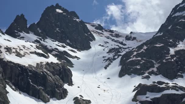 Esquiadores Lejanos Deslizándose Por Ladera Nevada Con Rocas Oscuras Parque — Vídeo de stock