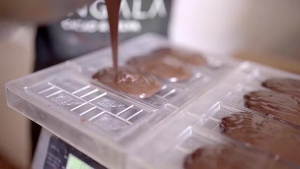 現代の菓子の仕事の間にプラスチック棒型に液体のチョコレートを注ぐ作物の認識できない人の高い角度 — ストック動画