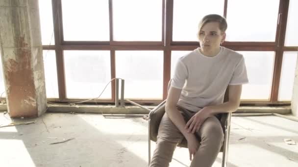 Kendine Güvenen Genç Düşünceli Bir Adam Boş Bir Salonda Oturuyor — Stok video