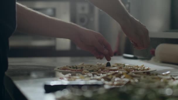 stock video Cropped male cook preparing pizza with various vegetables on marble counter with ingredients and utensils in pizzeria kitchen