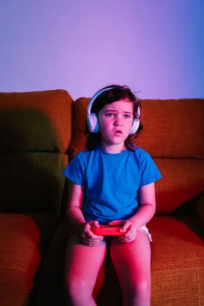 Ragazza Sconvolta Cuffia Giocare Interessante Videogioco Con Gamepad Mentre Seduto — Foto Stock