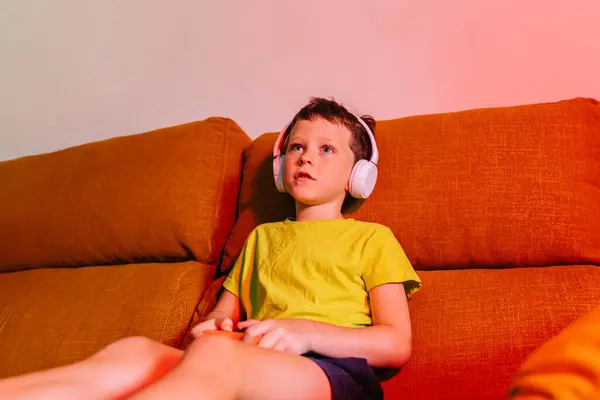 Skupiony Chłopiec Słuchawkach Bezprzewodowych Gamepadem Podczas Gry Wideo Kanapie Salonie — Zdjęcie stockowe