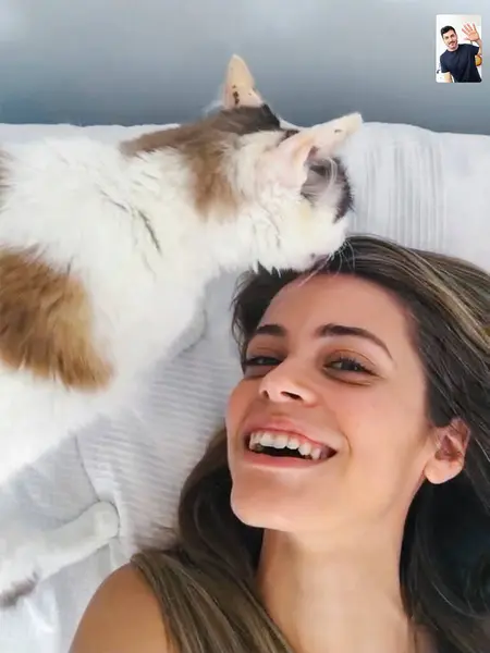 Cat kissing her owner while she is doing a video call with a friend in Coronavirus quarantine.