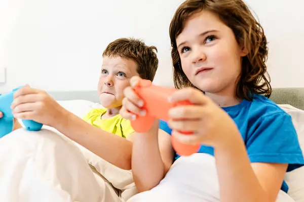 Irmãos Focados Com Gamepads Jogando Videogame Interessante Enquanto Sentados Juntos — Fotografia de Stock
