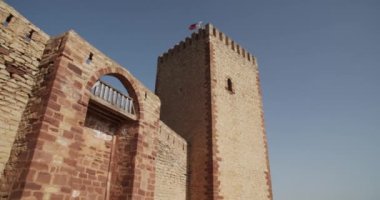 Tepsinin altından, güneşli bir günde mavi bulutsuz gökyüzünün arka planında taş cepheli kuleleri olan antik kalenin sağ görüşü.