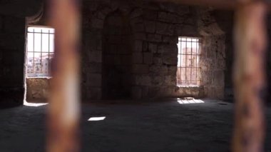 Paslı, terk edilmiş, taş duvarları yıpranmış, Lübnan 'ın güneşli camlarında ızgaraları olan terk edilmiş, paslı metal bir binanın içinden.