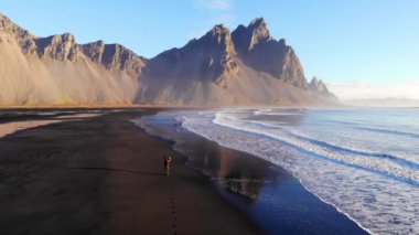 Fırtınalı İzlanda 'da fırtınalı bir günde dalgalı deniz dalgalarının dalgalı kayalıkların yanında yuvarlanışını ve sıçrayışını gösteren resimli drone görüntüsü.