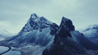 İzlanda 'da kış akşamları bulutlu gökyüzüne karşı karlı dağ sırtı manzarası