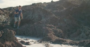 Tenerife, Kanarya Adaları, İspanya 'da deniz gayzeri yakınlarında volkanik deniz kıyısında yürüyüş yapan sıradan kıyafetli olgun bir adamın fotoğrafını çekiyorum.