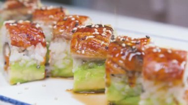 Şefin tabağı çevirdiği yüksek açılı yakın plan fotoğraf ve taze somon dilimleri ve lezzetli sosla süslenmiş pilav ile modern restoranda lezzetli doğu yemekleri hazırlarken.