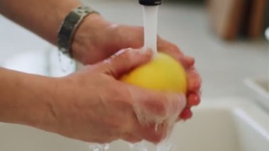 Gerçek zamanlı anonim bir kadın mutfak lavabosundaki musluktan limon yıkıyor.