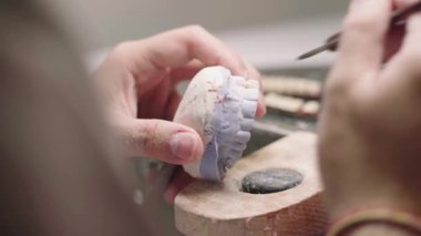 Laboratuvarda takma diş üretirken alçı çene ve seramik dişleri şekillendiren tanınamayan erkek üstadın yakınlaştırılması