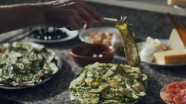 Kesilmiş erkek, pizzayı mermer tezgahta çeşitli sebzelerle hazırlıyor.