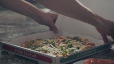 Tanınmayan erkek pizzacılar pizzacıda çalışırken taze pişmiş lezzetli pizzaları karton kutuya koyarlar.