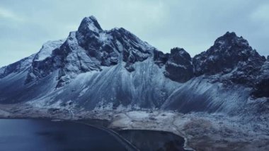 İzlanda 'da kış akşamları bulutlu gökyüzüne karşı karlı dağ sırtı manzarası