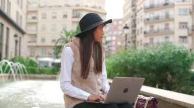 Konsantre olmuş İspanyol kadın internet sayfasında yazıyor. Binanın yakınında. Sokakta kahve servisi var.