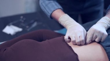 Güzellik merkezinde özel ekipmanlarıyla piercing yaptıran bir kadın..